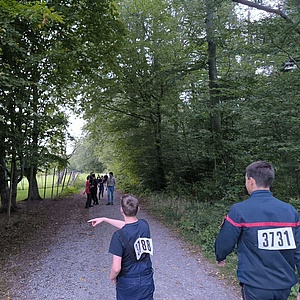 Jugendliche in Feuerwehruniform und Tracht tragen Nummern auf den Rücken geheftet um sich im Spiel gegenseitig abzurufen